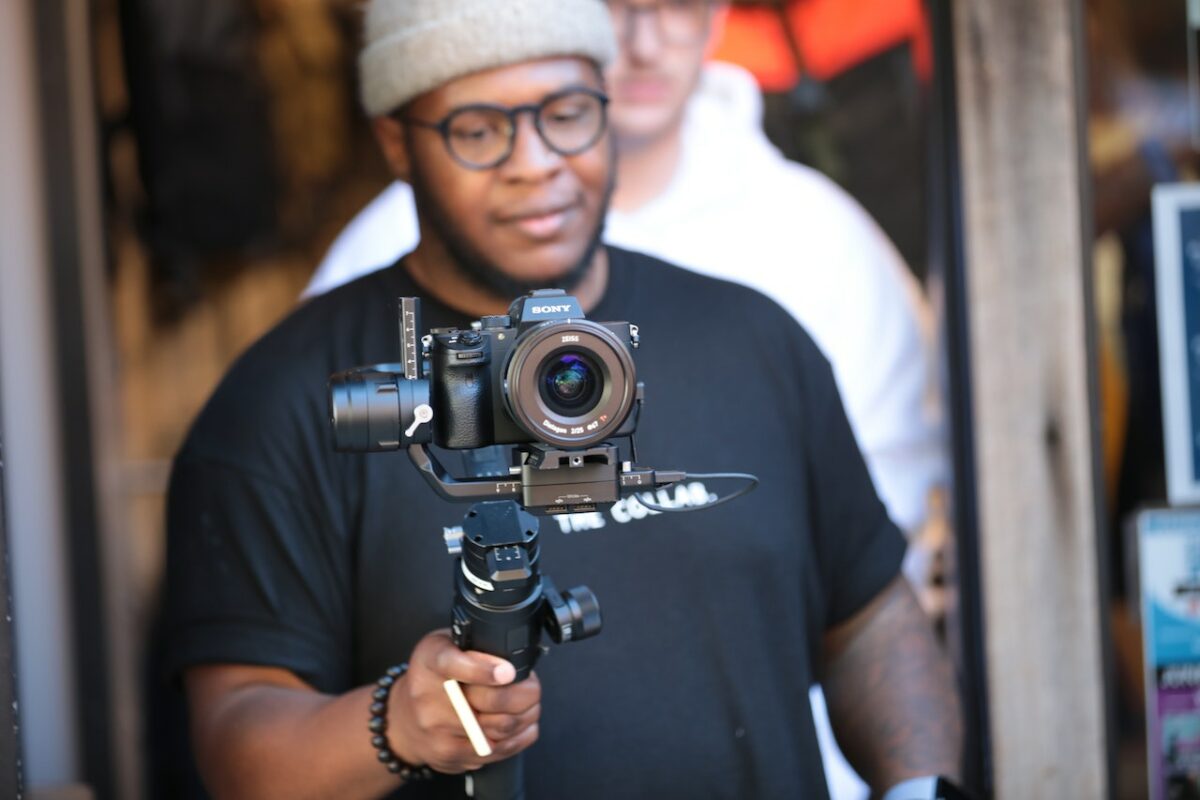 A man wearing a black t-shirt using a black gimbal and a Sony camera