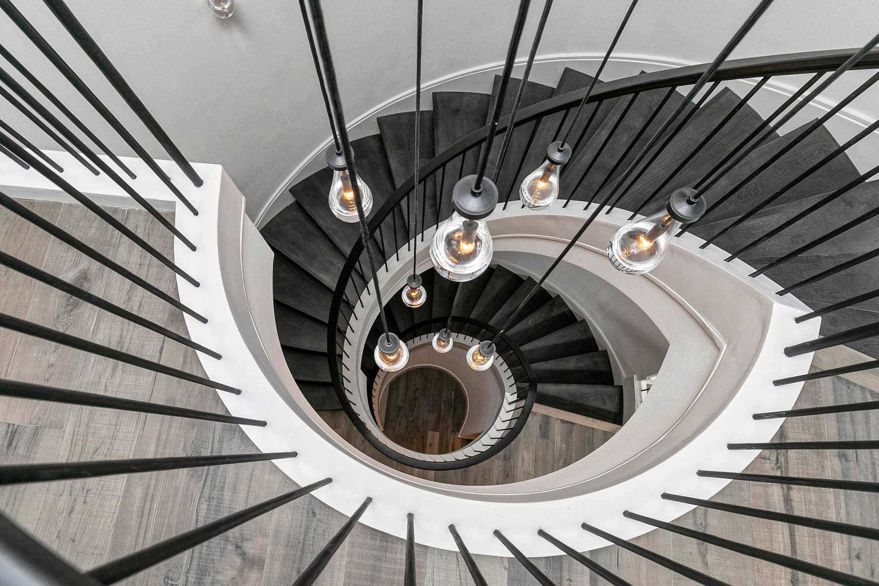 Aesthetically pleasing structure of a white circular stairwell with long light fixtures